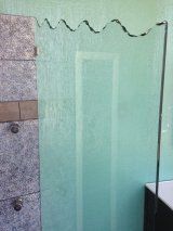 A bathroom with a glass shower door and a tiled wall