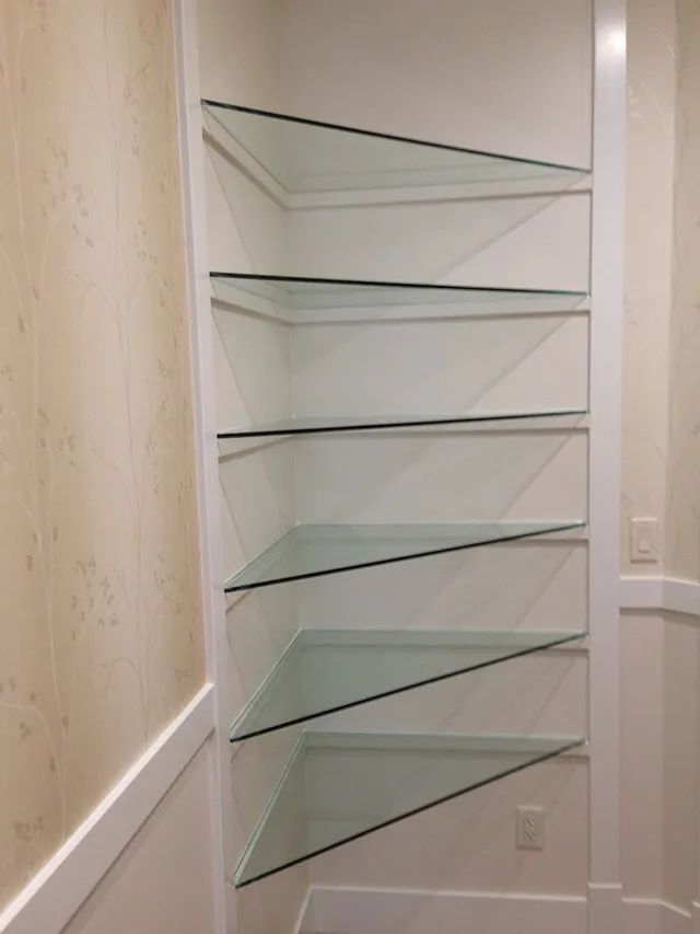 A set of glass shelves in a corner of a room