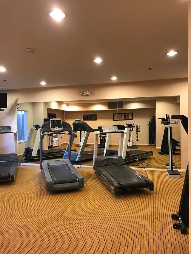 A gym with a lot of treadmills and a mirror