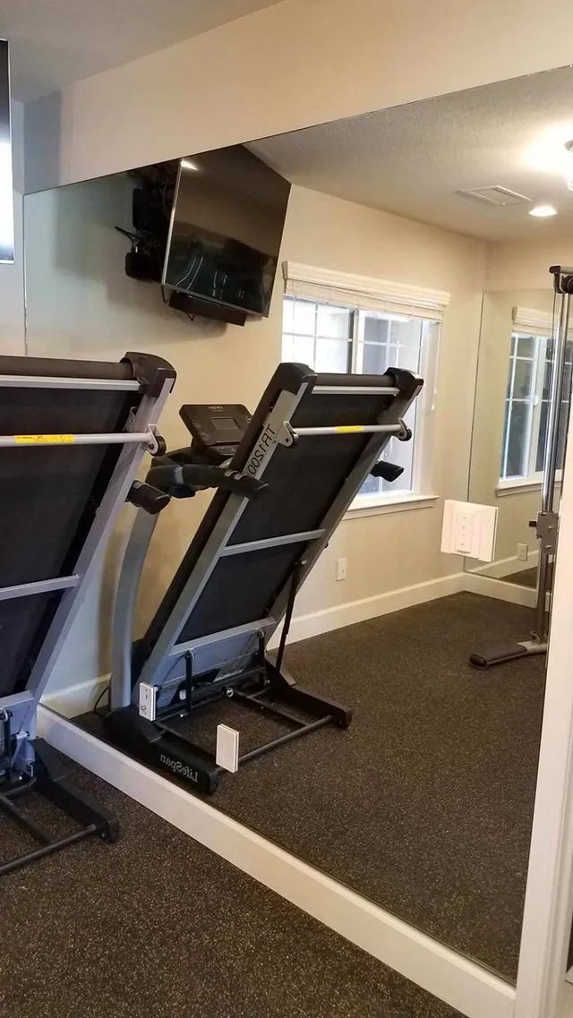 A treadmill is sitting in front of a large mirror in a gym
