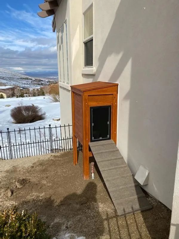 A wooden pet access point has been installed on the side of the house