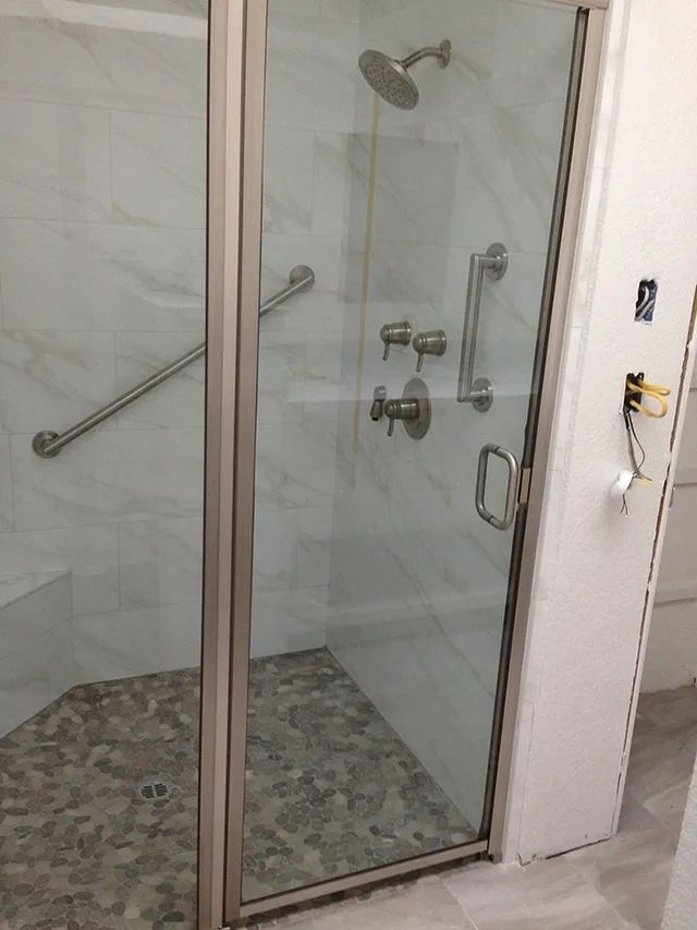 A bathroom with a walk-in shower with a glass door and a shower head