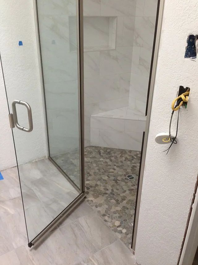 A bathroom with a walk-in shower with a glass door