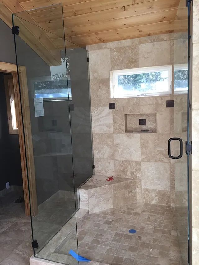 A bathroom with a walk-in shower with a glass door