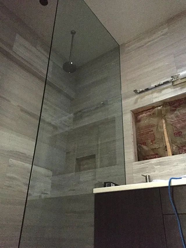 A bathroom with an enclosed shower and a sink