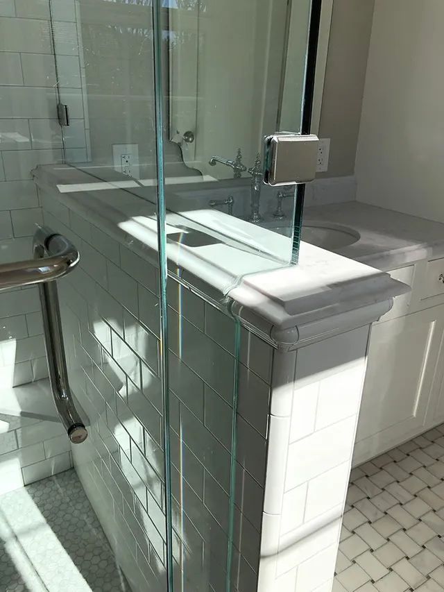 A bathroom with a glass shower door and a sink