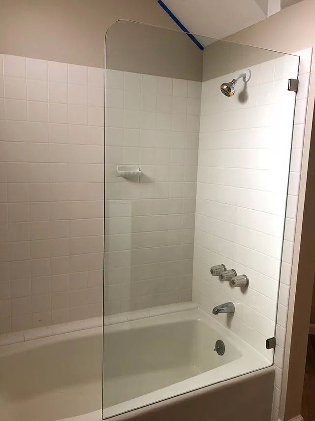 A bathtub in a bathroom with a glass shower door