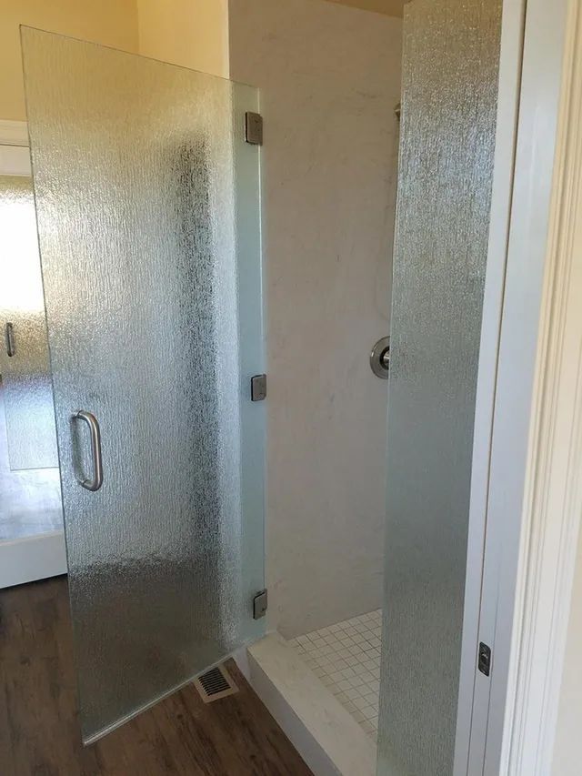 A bathroom with a walk-in shower and a glass door