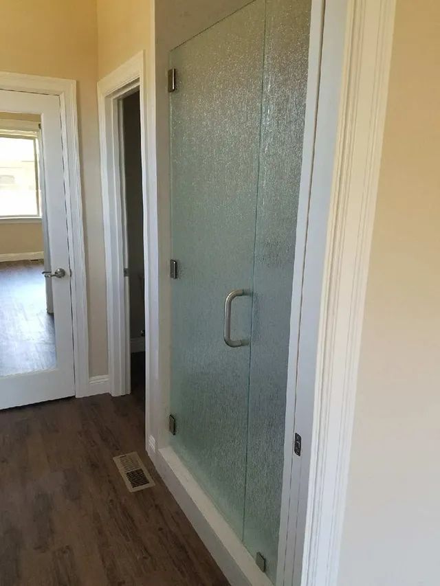 A bathroom with a walk-in shower and a glass door