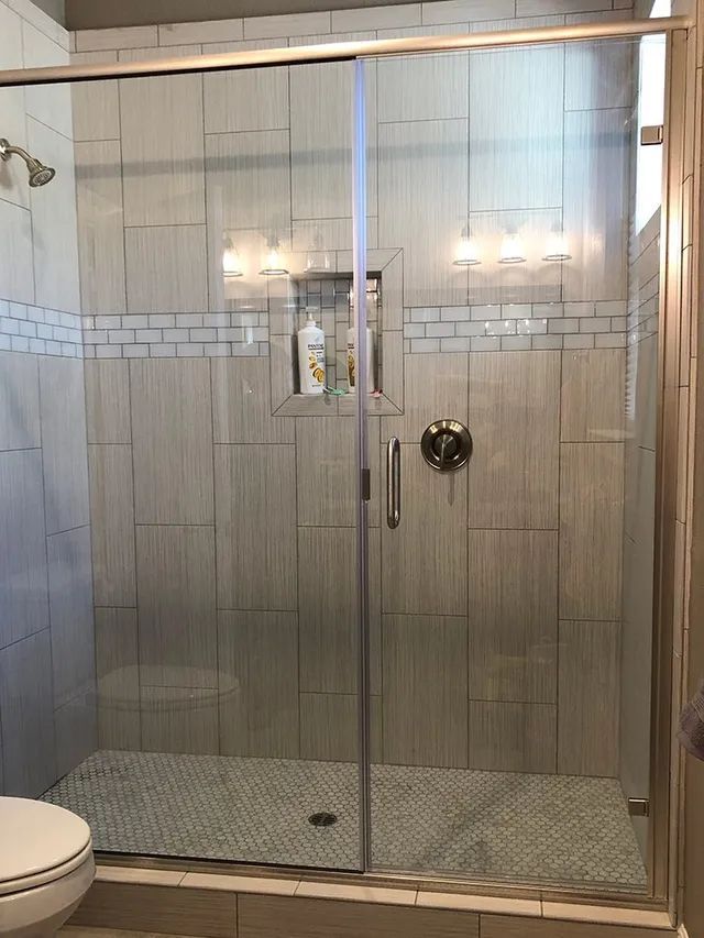 A bathroom with a sliding glass shower door and a toilet
