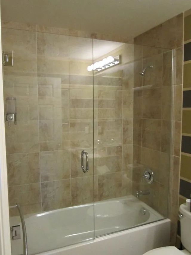 A bathroom with a bathtub and a toilet and a glass shower door