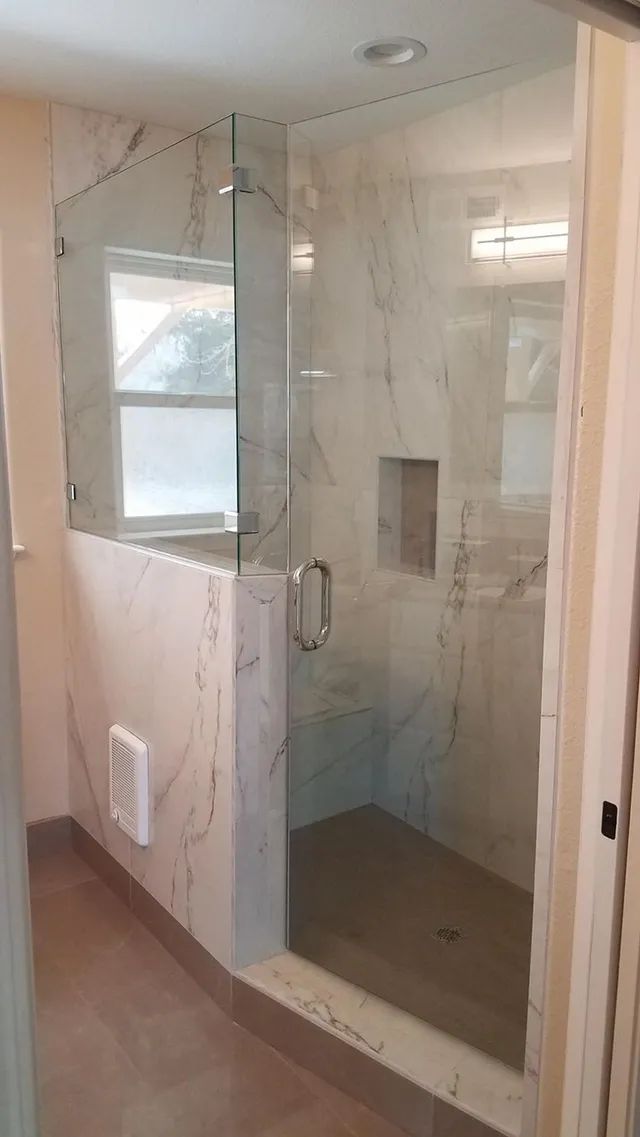 A bathroom with a walk-in shower with a glass door