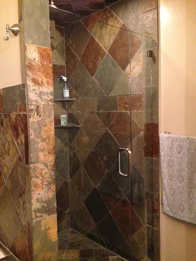 A bathroom with a walk-in shower with a glass door