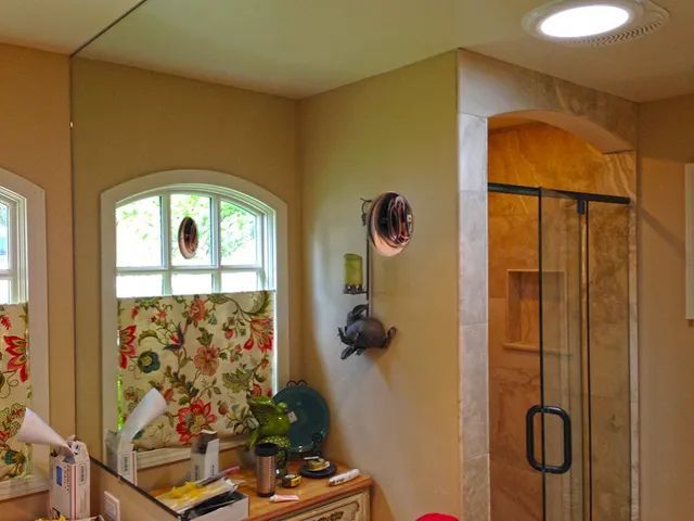 A mirror reflecting a bathroom with a sliding glass shower door