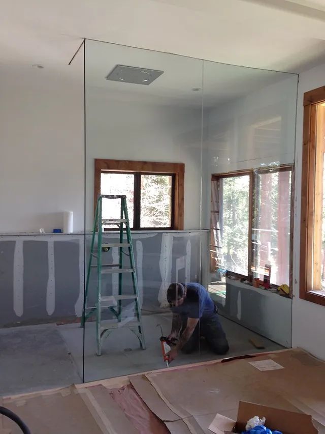 A man is installing a glass partition in a bathroom
