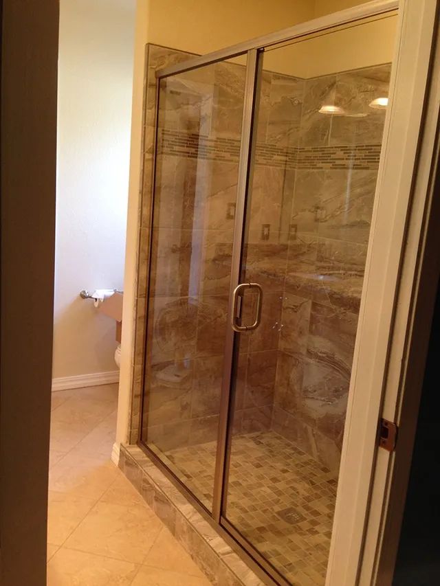 A bathroom with a walk-in shower with a glass door