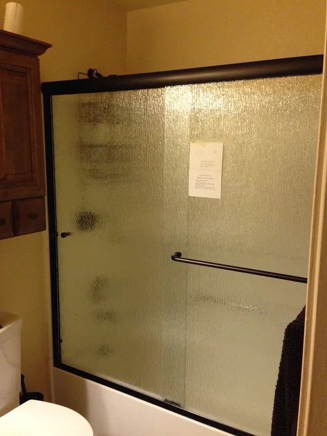 A bathroom with a walk-in shower with a glass door