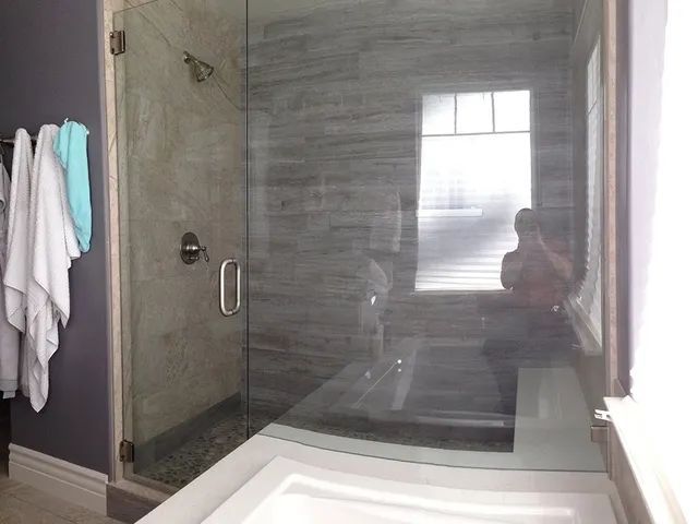 A bathroom with a walk-in shower, sink, and mirror