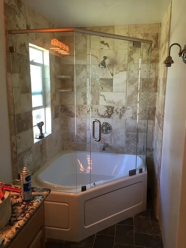 A bathroom with a tub and a shower with glass doors