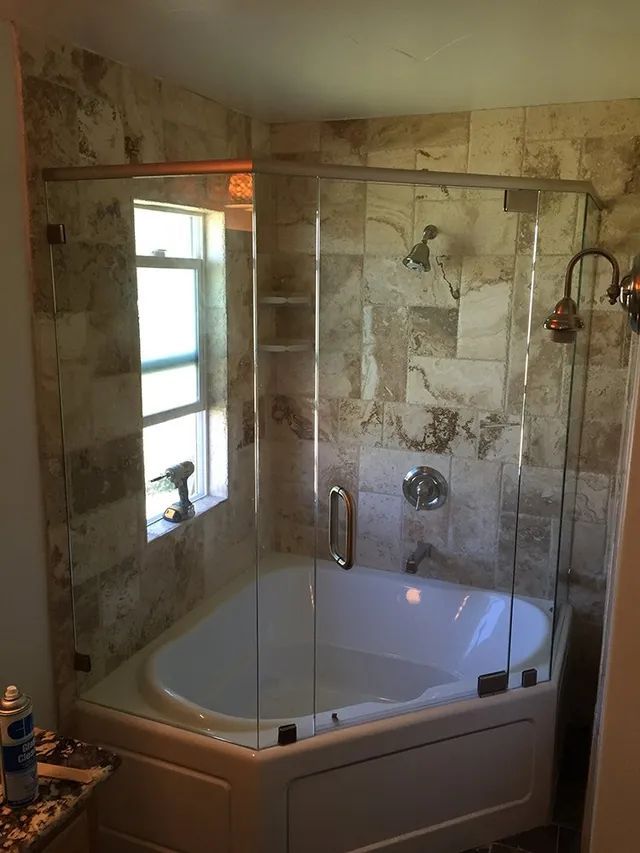 A bathroom with a tub and a shower with glass doors