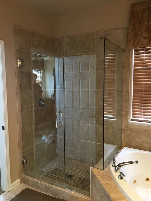 A bathroom shower with a glass enclosure and a bathtub