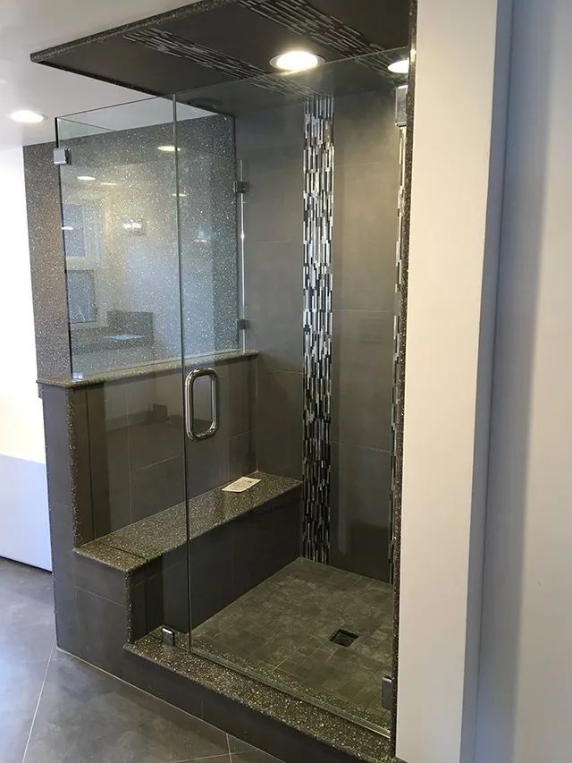 A bathroom with a walk-in shower with a glass door