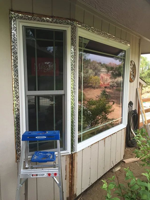 A blue ladder is sitting next to a window on the side of a house