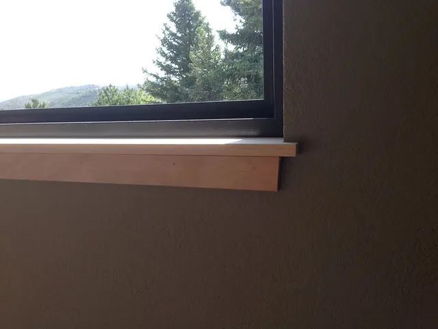 A window with a wooden sill and a view of trees in a room