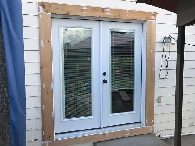 A white door with a wooden frame on a white house