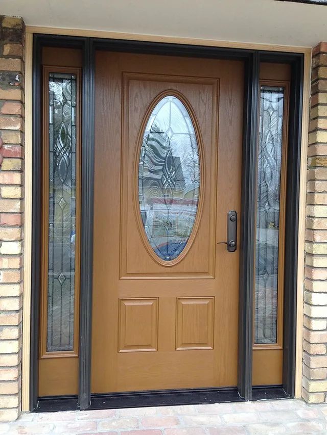 A brown door with a stained glass window is on a brick building
