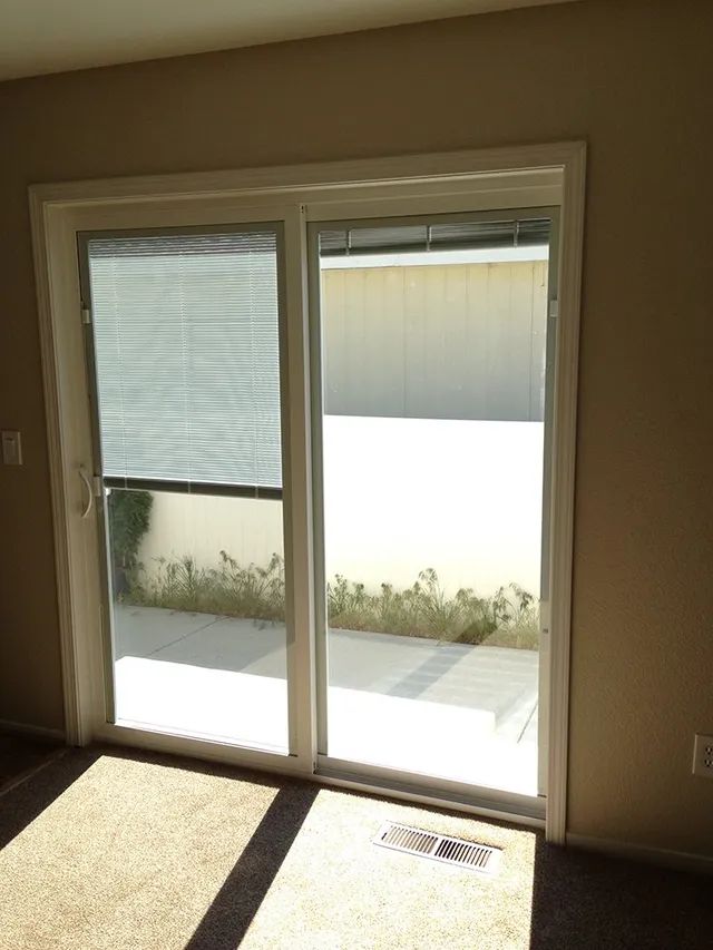 A room with a sliding glass door and blinds