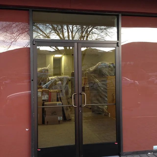 A commercial unit featuring a glass wall and door, complemented by red wallpaper