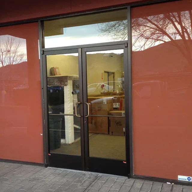 A commercial unit featuring a glass wall and door, complemented by red wallpaper