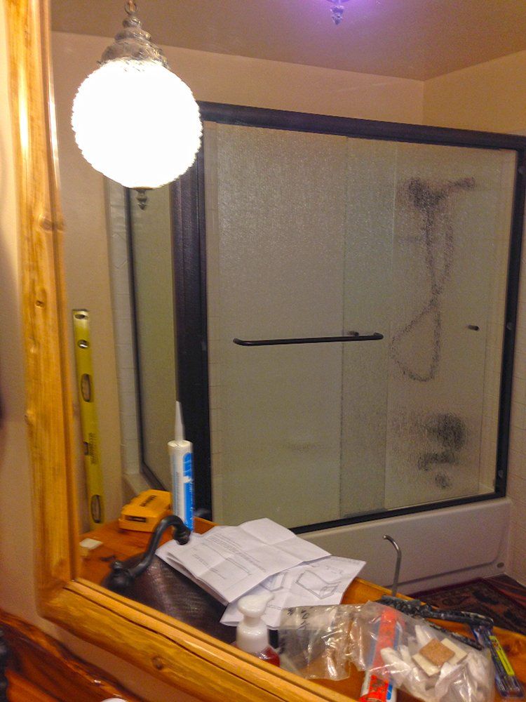 A bathroom with a sliding glass shower door and a mirror
