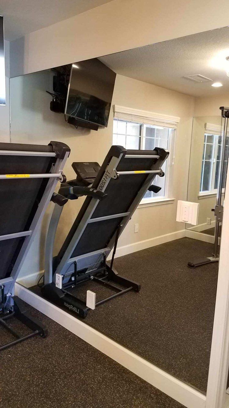 Two treadmills are sitting in a gym next to a large mirror
