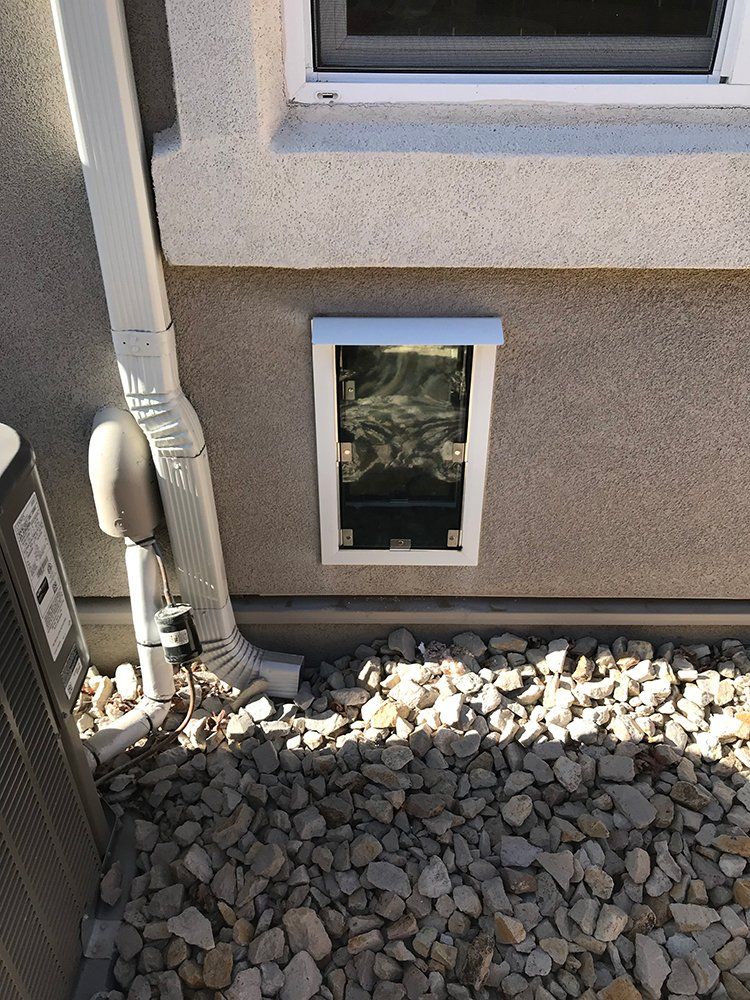 A dog door is installed on the side of a house next to a window