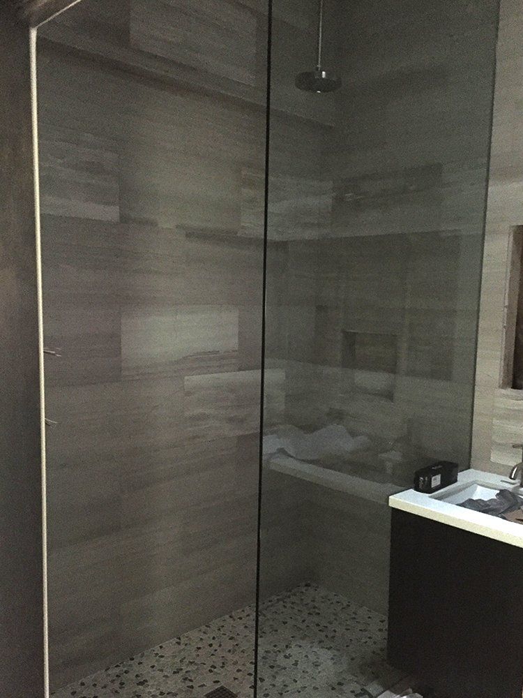 A bathroom with a walk in shower and a sink