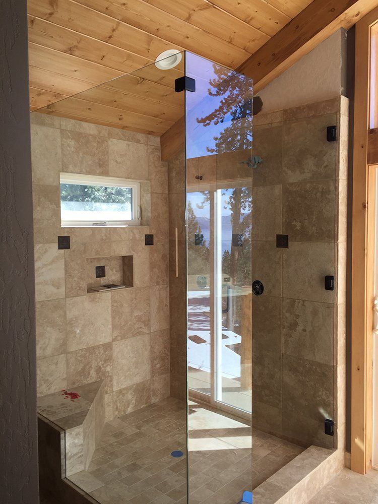 A bathroom with a walk in shower with a glass door