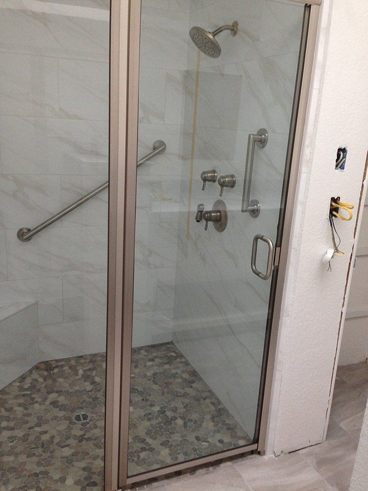 A bathroom with a walk in shower with a glass door and a shower head