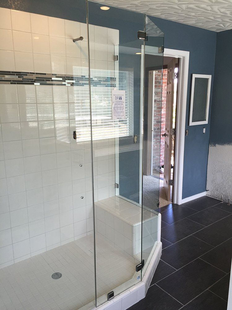 A bathroom with a walk in shower with a glass door