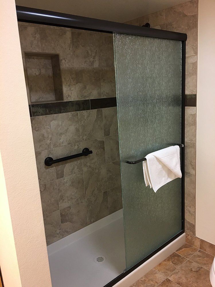 A bathroom with a sliding glass shower door and a towel rack