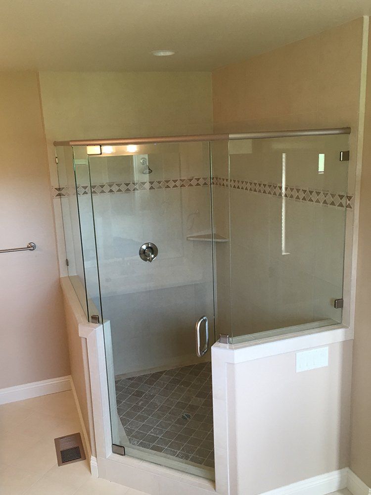 A bathroom with a walk in shower with a glass door