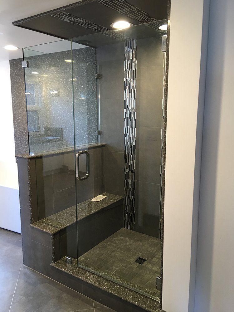 A bathroom with a walk in shower with a glass door