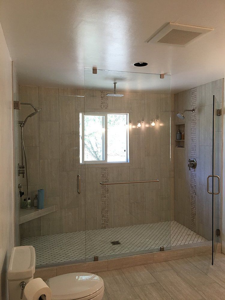 A bathroom with a toilet, shower, and window.
