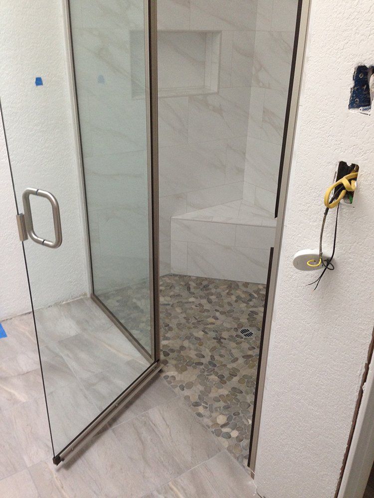 A bathroom with a walk in shower with a glass door