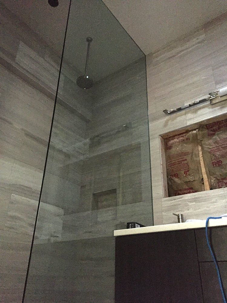 A bathroom with a walk in shower and a sink