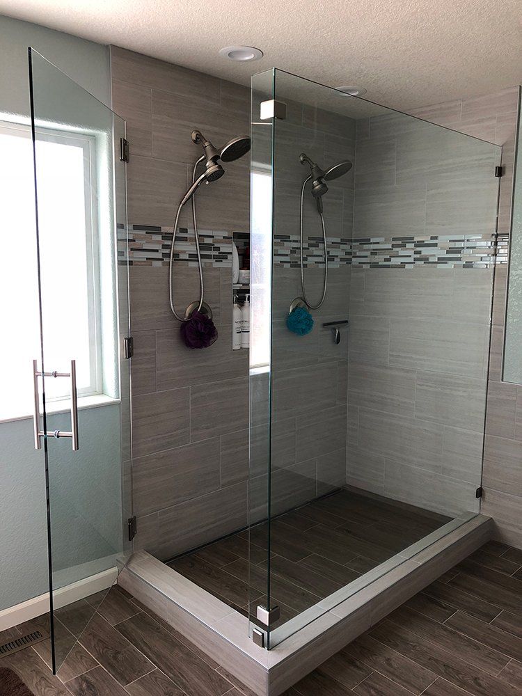 A bathroom with a walk in shower with a glass door and a window