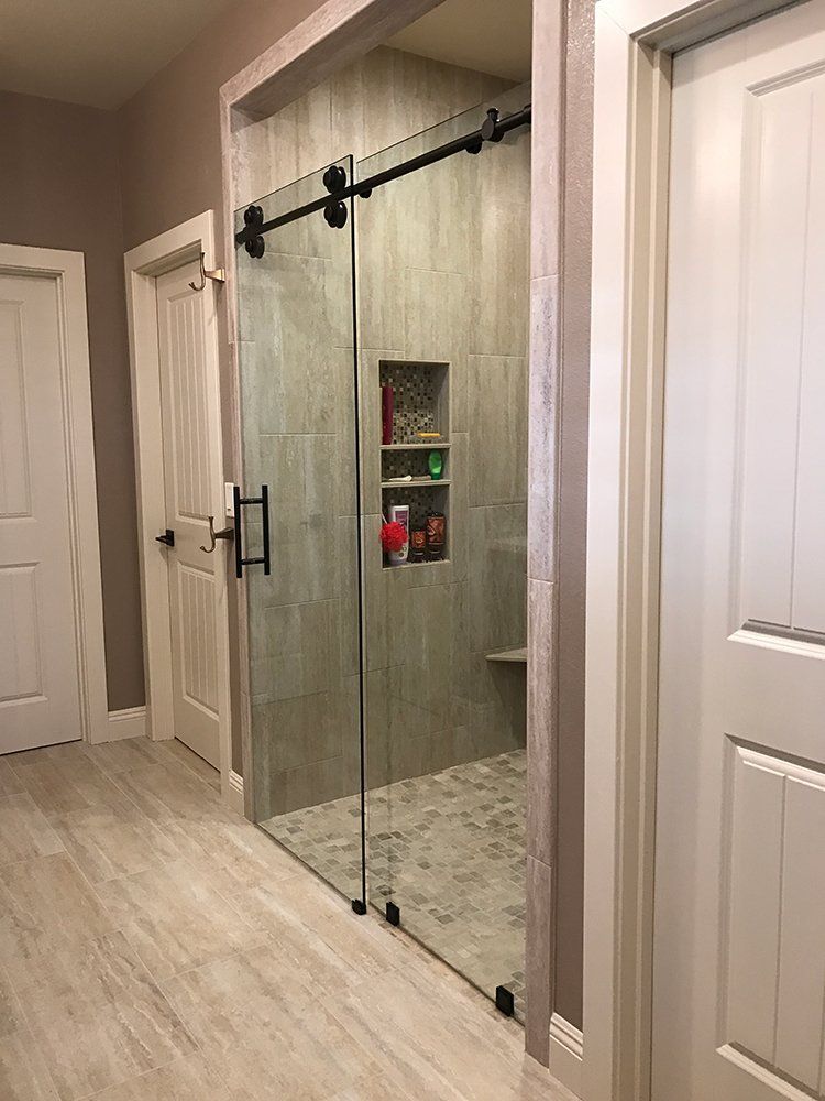 A bathroom with a walk in shower with sliding glass doors