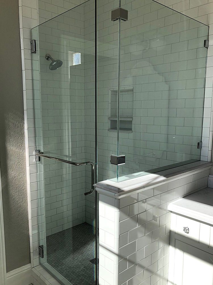 A bathroom with white tiles and a glass shower door