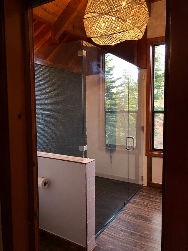 A bathroom with a walk in shower and a chandelier hanging from the ceiling